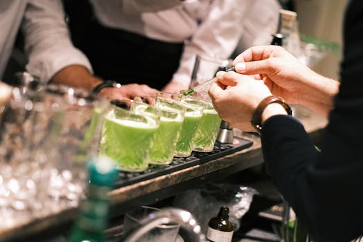 Close-up of bartender preparing vibrant green cocktails in a stylish Parisian bar.