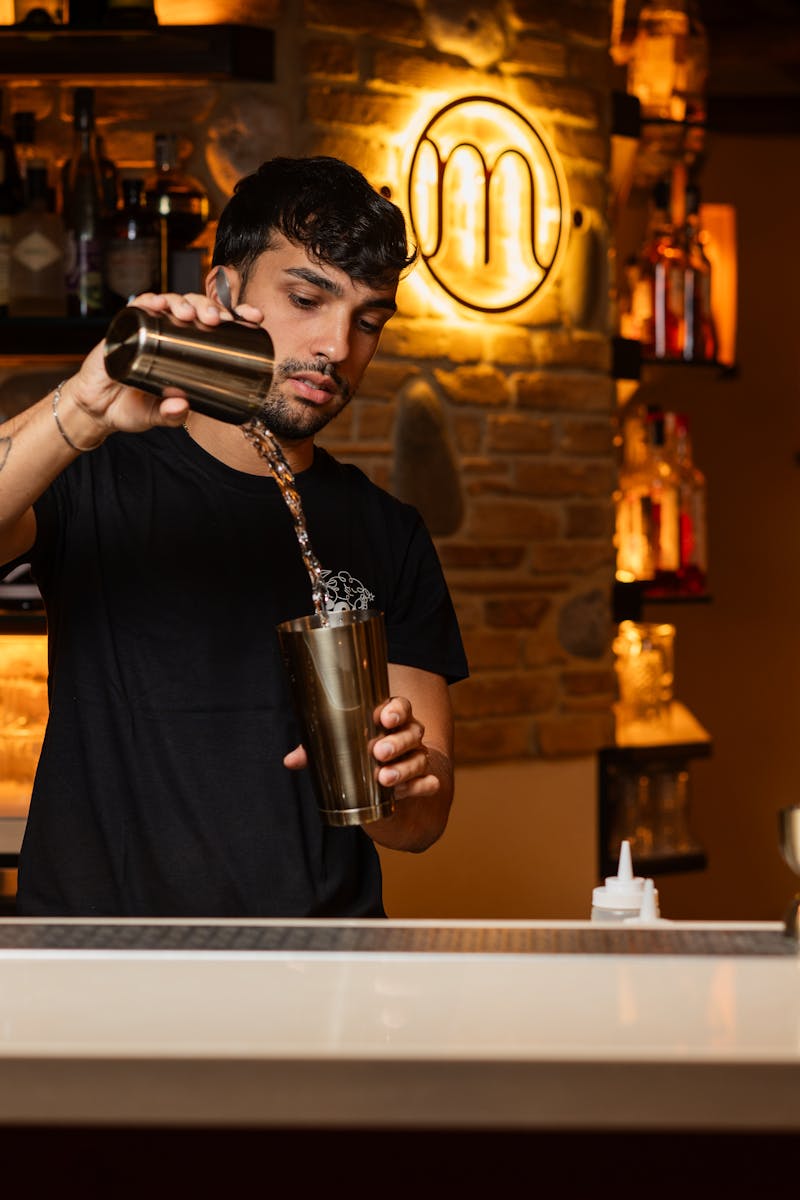 A bartender skillfully mixing a cocktail in a trendy bar setting, showcasing expert bartending skills.